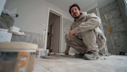 Carreleur posant un carrelage grand format dans une salle de bain moderne en 2025